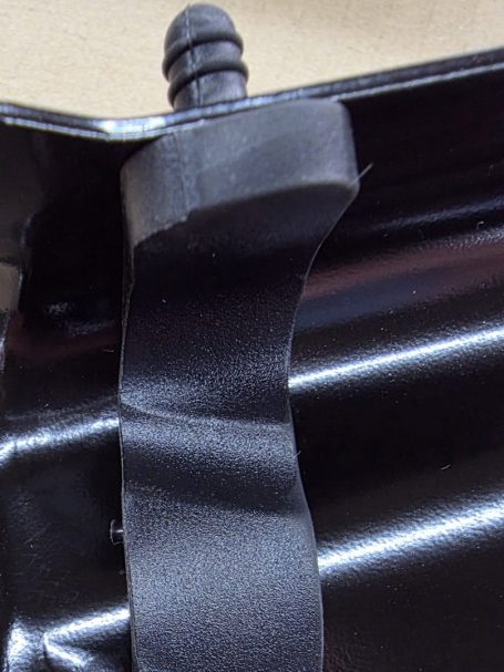 Schwarzes Kunststoffteil mit einer Ausbuchtung und einem kleinen Stift.