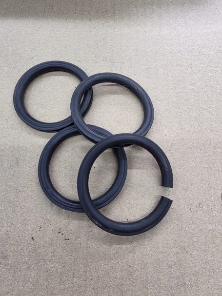 Vier schwarze Gummiringe auf einem hellen Hintergrund.