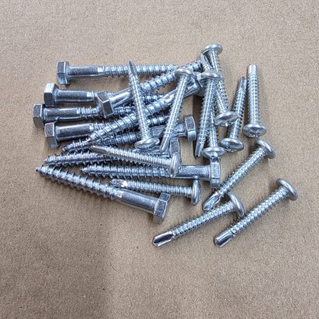 Eine Ansammlung von silbernen Schrauben auf einem braunen Untergrund.