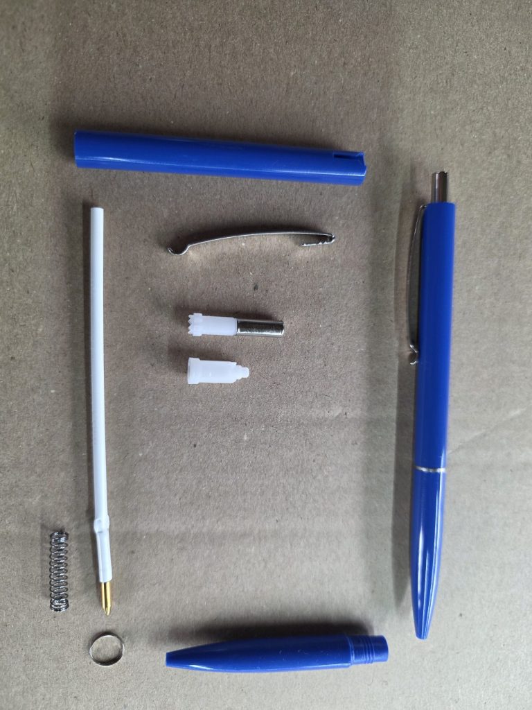 Blaue Schreibgeräte und Zubehörteile auf einem Karton.