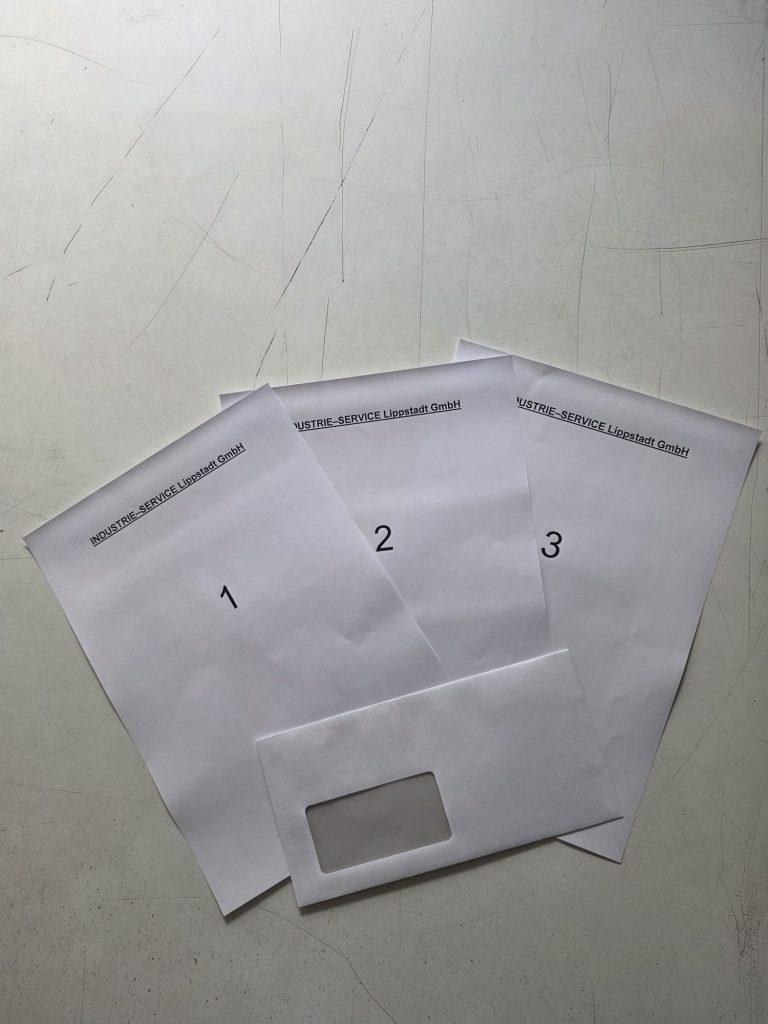 Drei beschriftete Blätter mit der Nummerierung 1, 2 und 3, ein Umschlag darunter.