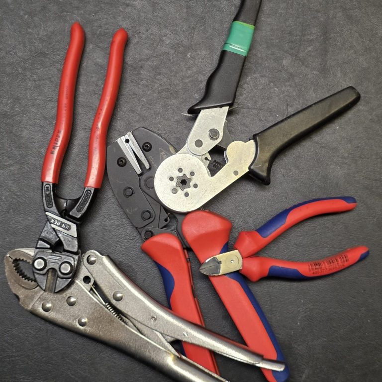 Kompetenz im Umgang mit mehreren Werkzeugtypen Diverse Zangen und Werkzeuge auf einem dunklen Hintergrund angeordnet.