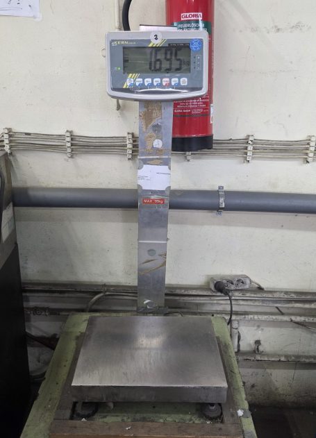 Digitale Waage auf einer Plattform in einer Werkstatt.